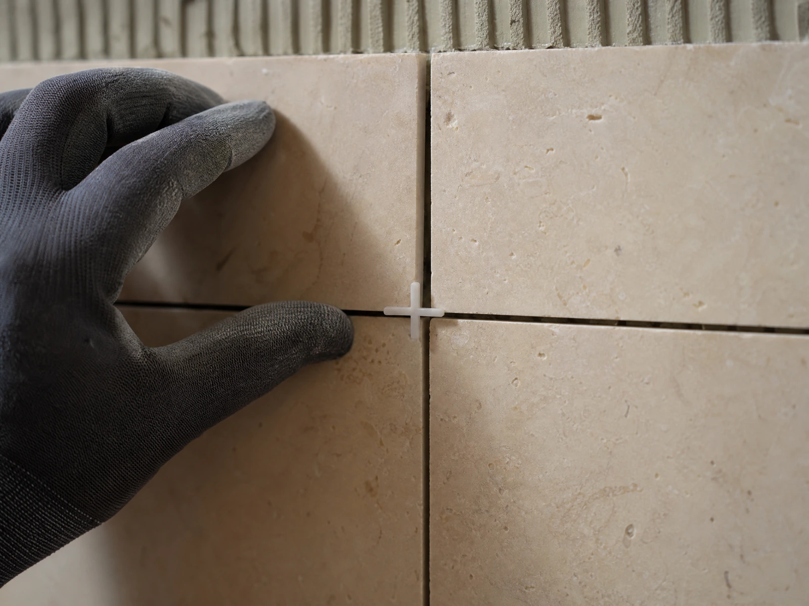Professional tile installer aligning ceramic wall tiles and grout lines